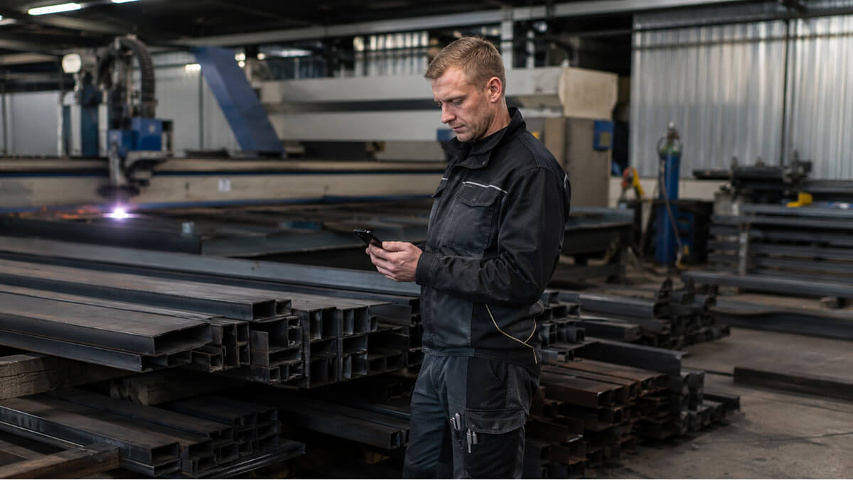Metallbauer pr&uuml;ft Angebot auf dem Smartphone in der Werkstatt